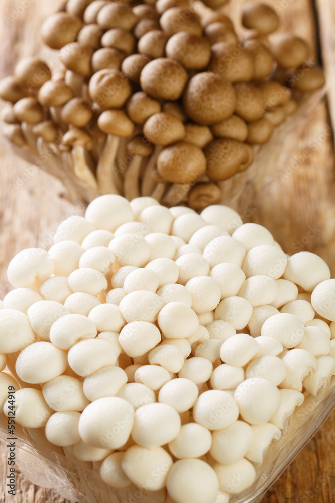 Fresh beech mushrooms or Shimeji or buna and bunapi in plastic container closeup on wooden table. Vertical Fresh beech mushrooms or Shimeji or buna and bunapi in plastic container closeup on wooden table. Vertical