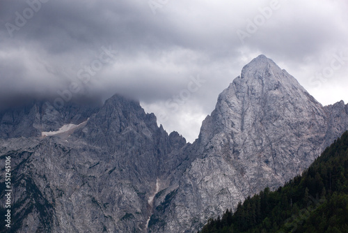 the rocky peaks in the clouds in the Triglav national park in Slovenia. The tops of the mountains are in the clouds. The softwood forest is under the bare peaks. © Florent Baudy 