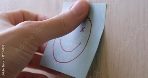 Man sticks a blue sticker with a funny face on the wall. The concept of good mood, positivity, luck, psychology, optimism, luck. 4K video.