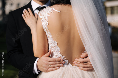 Middle celection of groom hug his bride outdoors. Wedding concept. Back view of bride dress