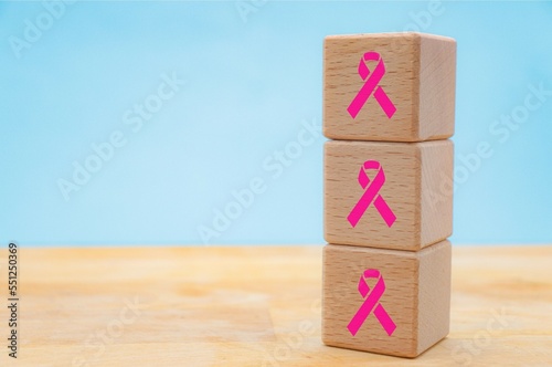  Breast cancer concept with wooden blocks cubes on blue background. Symbol of breast cancer, fist with strength concept. Healthcare, international women day and world cancer day.