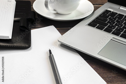 Online work. a desktop with a laptop, a clean notebook, a coffee cup and a pen on a wooden table. Freelance, copywriter