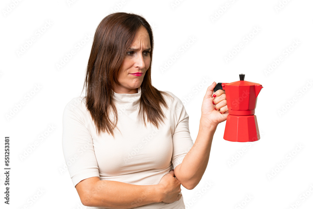 Middle-aged caucasian woman holding coffee pot over isolated background with sad expression Middle-aged caucasian woman holding coffee pot over isolated background with sad expression