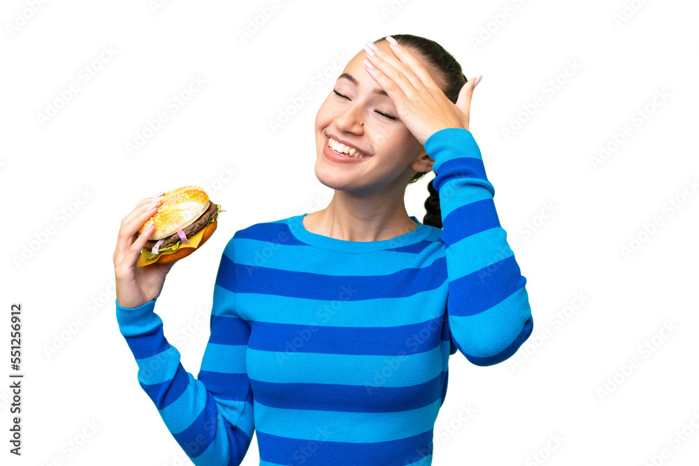 Young Arab woman holding a burger over isolated background smiling a lot Young Arab woman holding a burger over isolated background smiling a lot