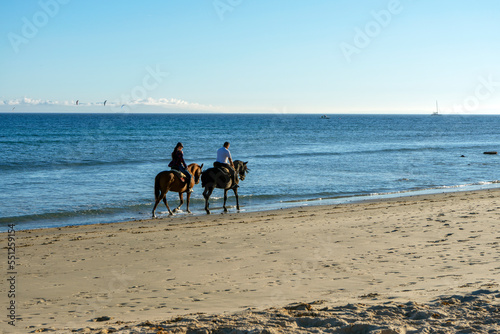 TARIFA, SPAIN - NOVEMBER 5, 2022: Horse walk on Valdevaqueros beach, Gibraltar Strait in Tarifa, Spain on November 5, 2022