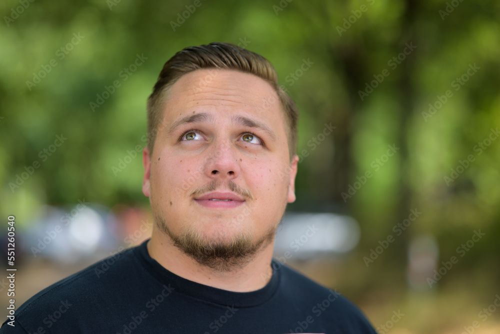 Young man with mustache standing looking up outdoors Young man with mustache standing looking up outdoors