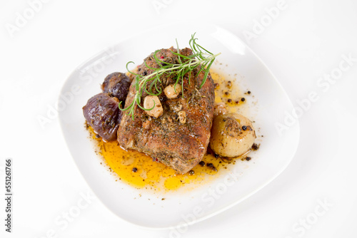 Roast pork loin with onions and garlic, decorated with rosemary and some colorful peppercorns