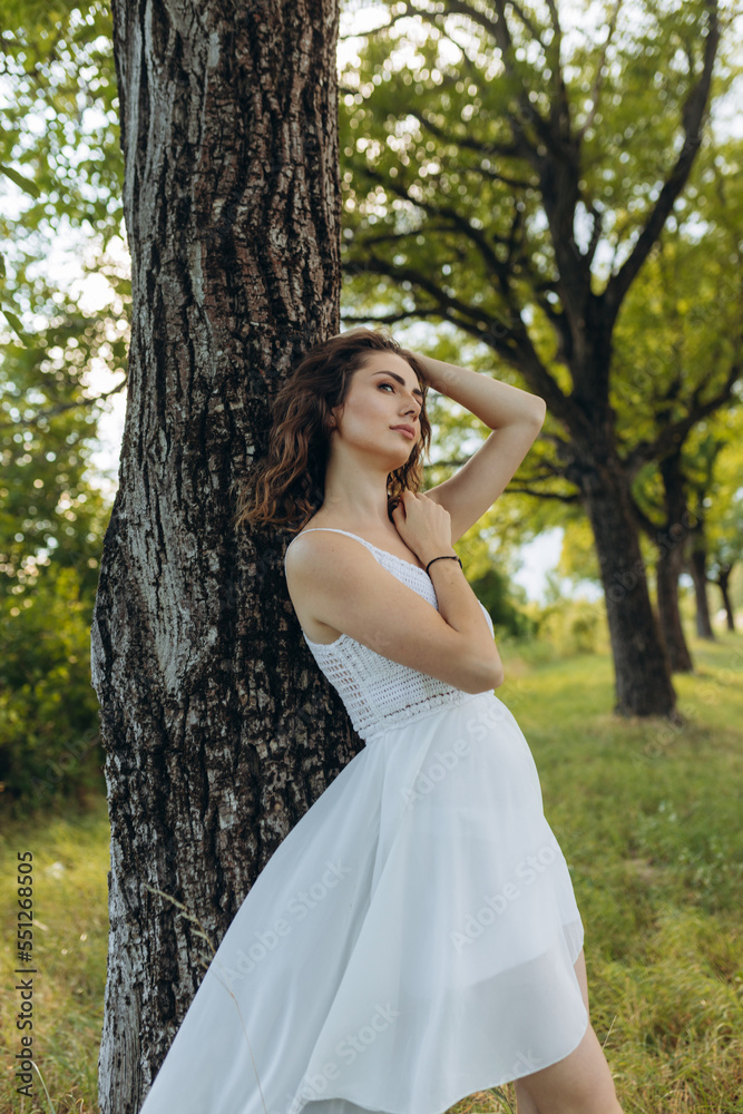 a girl in a white dress near a tree