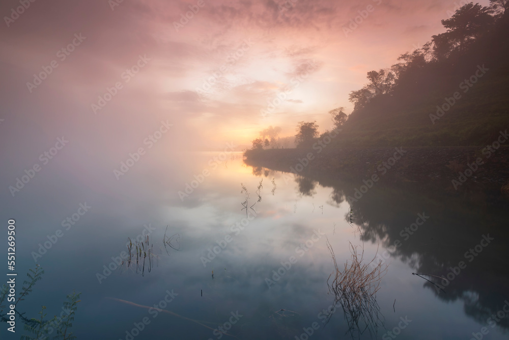 Fototapeta premium The water reflection of the sunrise breathtaking beauty nature scenery landscape with mountain mist in Khuean Phluang Reservoir nearby Khao Khitchakut National Park, Chanthaburi, Thailand