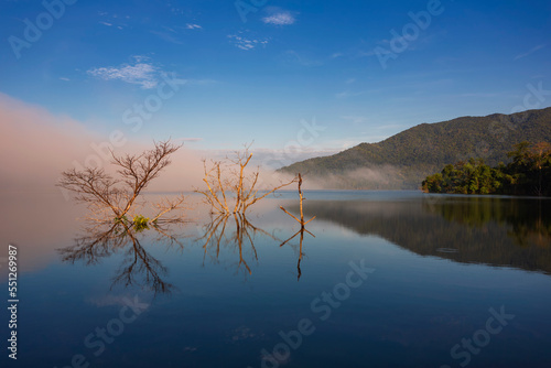 The water reflection of the sunrise breathtaking beauty nature scenery landscape with mountain mist in Khuean Phluang Reservoir nearby Khao Khitchakut National Park, Chanthaburi, Thailand 