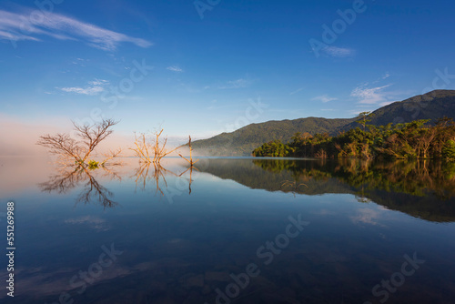 The water reflection of the sunrise breathtaking beauty nature scenery landscape with mountain mist in Khuean Phluang Reservoir nearby Khao Khitchakut National Park, Chanthaburi, Thailand 