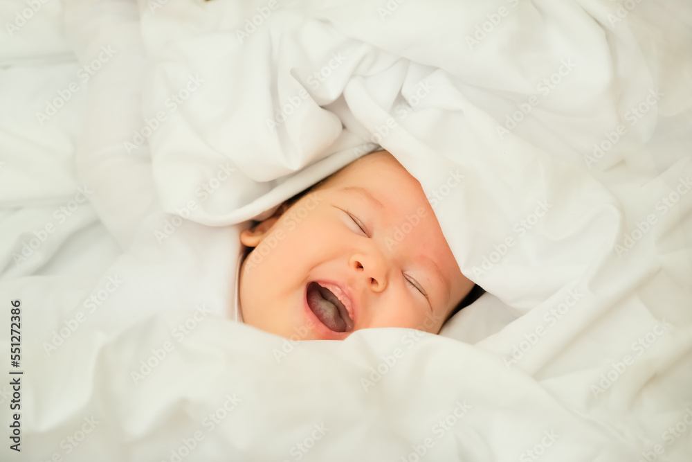 newborn baby smiles and laughs. shows emotions. baby lies on a white cloth newborn baby smiles and laughs. shows emotions. baby lies on a white cloth