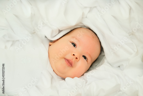 newborn baby smiles and laughs. shows emotions. baby lies on a white cloth