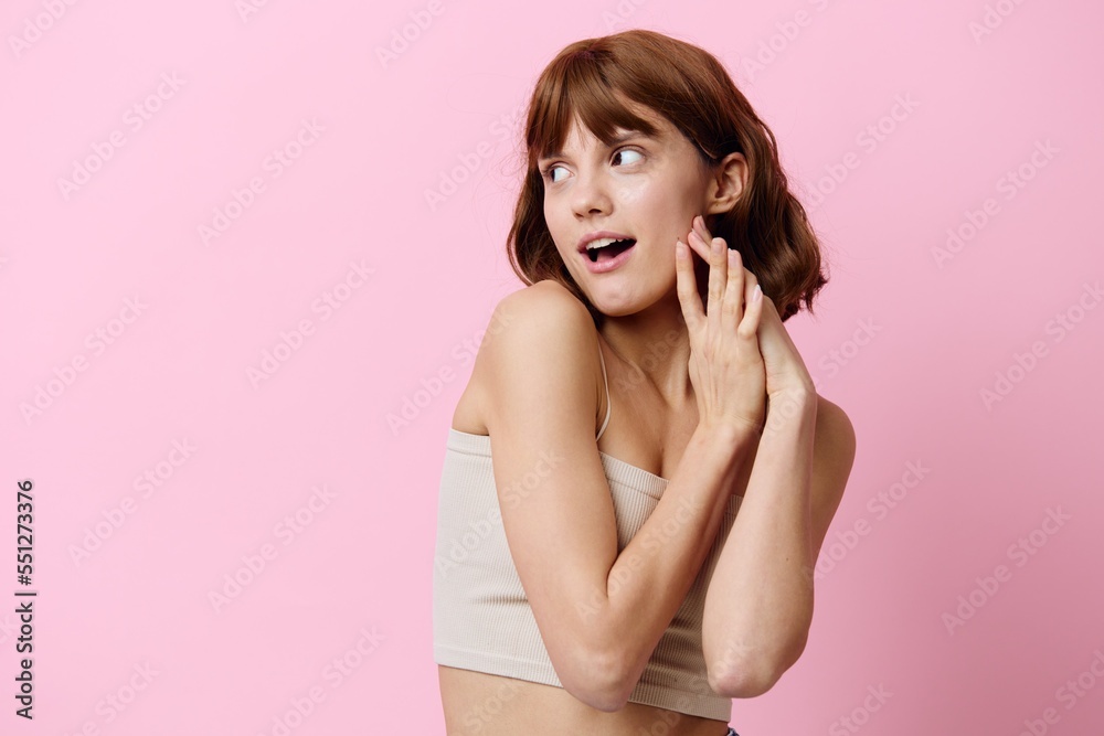 a happy, very emotional woman stands on a pink background with her mouth wide open in surprise and holds her hand near her face a happy, very emotional woman stands on a pink background with her mouth wide open in surprise and holds her hand near her face