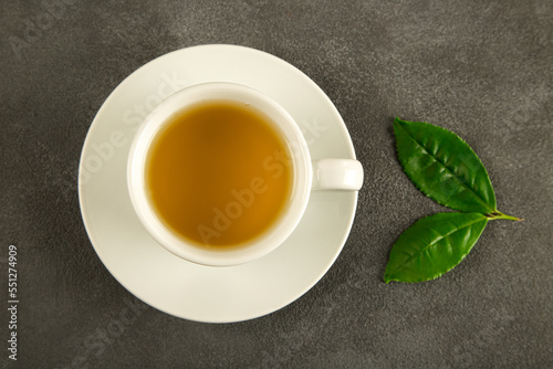 Tea leaves with a white cup of green tea,on black background