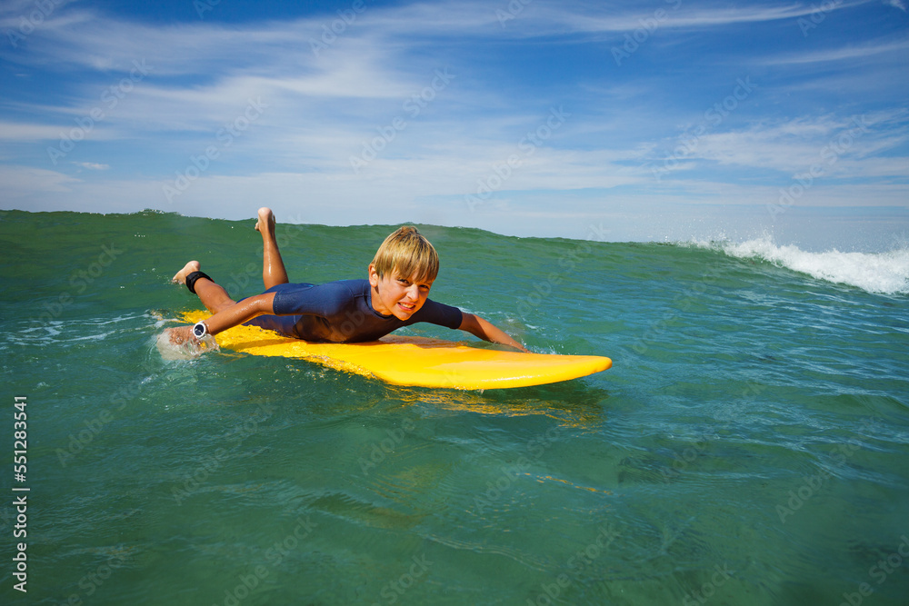 Boy lay on surf board and start paddling to catch the wave