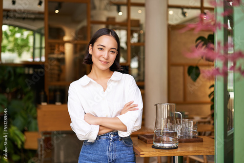 Portrait of smiling asian girl in white collar shirt, working in cafe, managing restaurant, looking confident and stylish photo