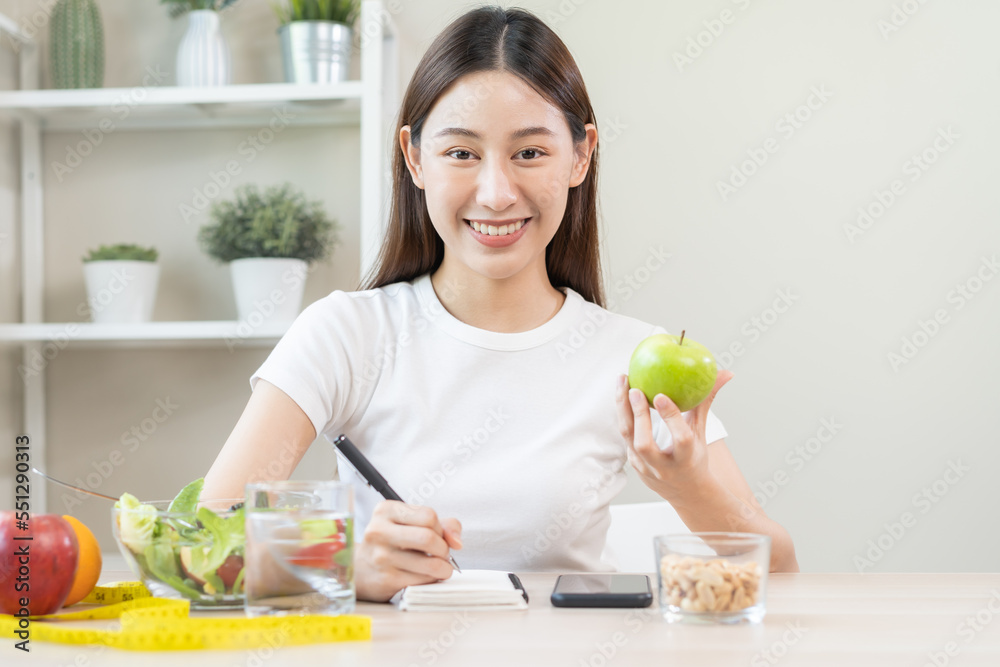 Diet, Dieting attractive asian young woman, girl working, write diet plan right nutrition with eat fresh vegetables salad is food for good health. Nutritionist for weight loss of healthy at home. Diet, Dieting attractive asian young woman, girl working, write diet plan right nutrition with eat fresh vegetables salad is food for good health. Nutritionist for weight loss of healthy at home.