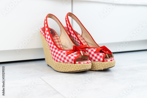 Red White open shoes with a high wedge heel in front of a closet photo