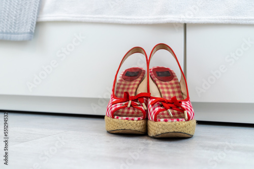Red White open shoes with a high wedge heel in front of a closet photo