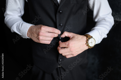 Portrait of a fashionable man fastening a button on his jacket, close-up. Wedding day.