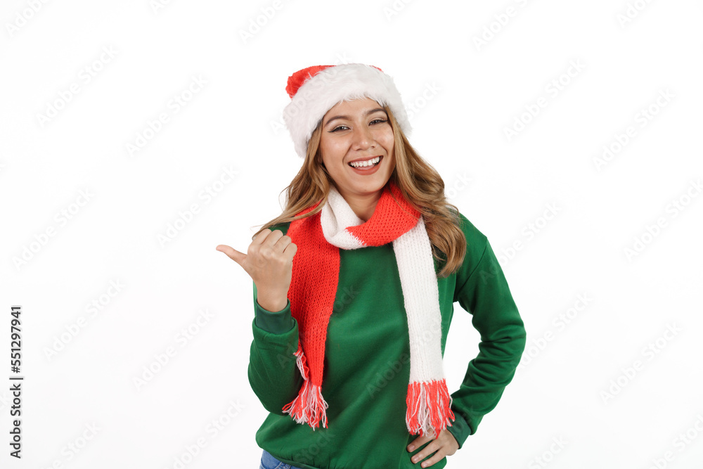 Attractive excited asian female in green sweater with santa hat on christmas isolated on white background. Pointing hand Attractive excited asian female in green sweater with santa hat on christmas isolated on white background. Pointing hand