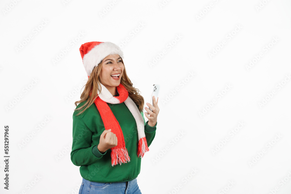 Attractive excited asian female in green sweater with santa hat on christmas isolated on white background. holding mobile smartphone Attractive excited asian female in green sweater with santa hat on christmas isolated on white background. holding mobile smartphone