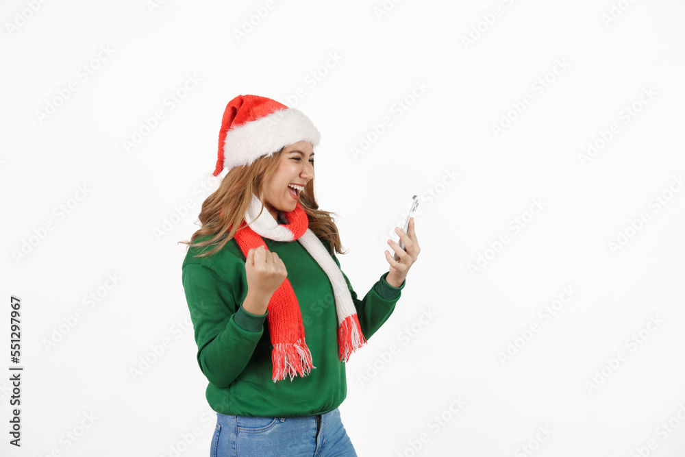 Attractive excited asian female in green sweater with santa hat on christmas isolated on white background. holding mobile smartphone