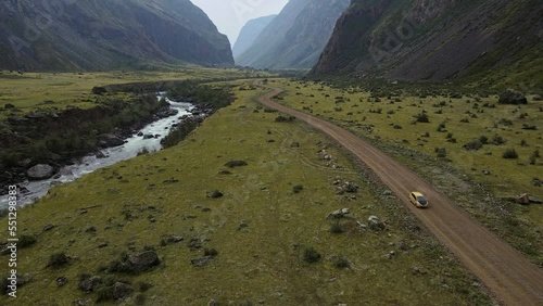 Aerial view of the picturesque valley. Car rides along the river on the road