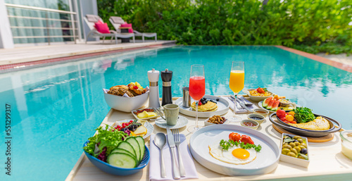 Breakfast in swimming pool  floating breakfast in luxurious tropical resort. Table relaxing on calm pool water  healthy breakfast and fruit plate by resort pool. Tropical couple beach luxury lifestyle