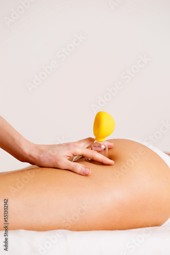 The masseuse performs a vacuum procedure on the thighs