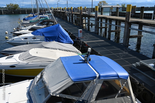  View on blue top boat roof cover or weatherproof fabric of small private motor yacht moored with other boats in marina. On the top are navigational lights.