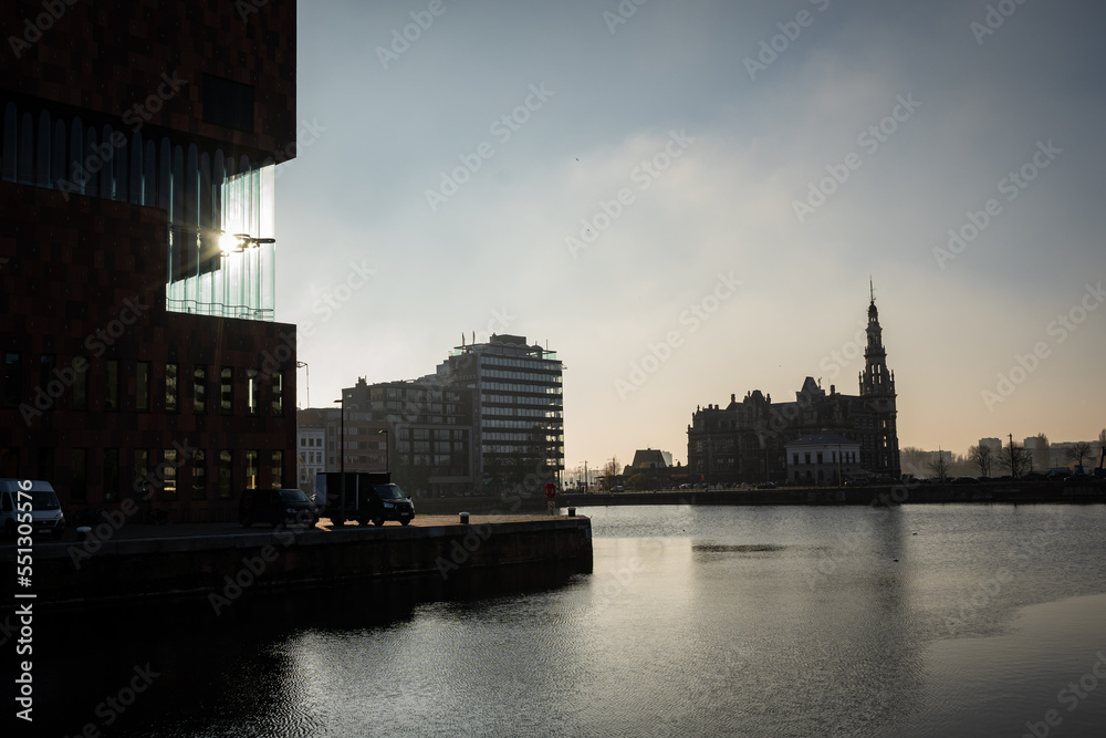 A silhouette accross the water catching the edge of the museum Aan de Stroom in the port of Antwerp Bruges portopolis and St Pauls church or sint pauluskerk in Flemish
