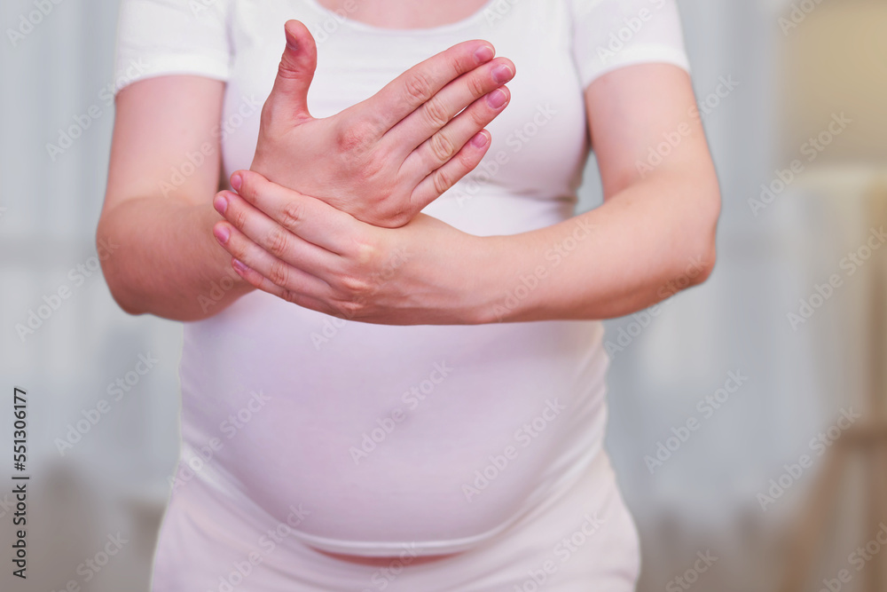 A pregnant woman holds her hand. Tunnel syndrome in the wrist during