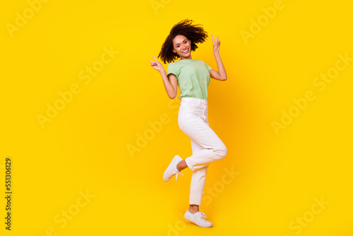 Full body size photo of young pretty attractive nice woman showing v-sign symbol toothy smile dance pose isolated on yellow color background