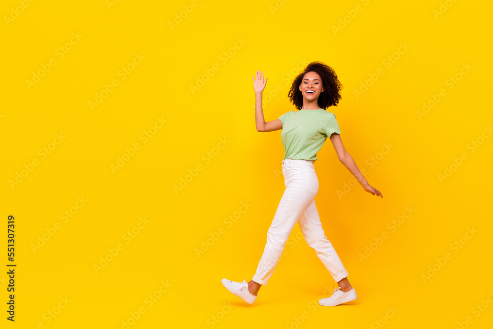 Full body size attractive adorable gorgeous nice woman wear green t-shirt white pants showing hello palm positive isolated on yellow color background Full body size attractive adorable gorgeous nice woman wear green t-shirt white pants showing hello palm positive isolated on yellow color background