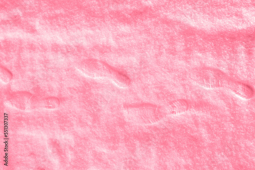 Several human footprints in shoes on freshly fallen snow toning in color of 2023 Viva Magenta.