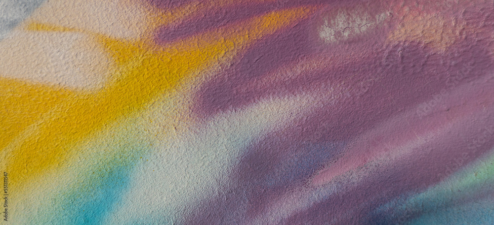 Obraz premium Fragment of old plaster wall with graffiti painting. Part of colorful street art graffiti on wall background. Youth, urban culture. Yellow, green, purple, light blue colors