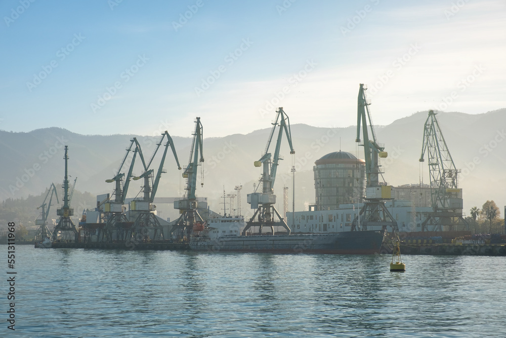 Batumi sea port with cranes silhouettes, ships, ferries at sunrise. Logistic, industry, shipping, concept