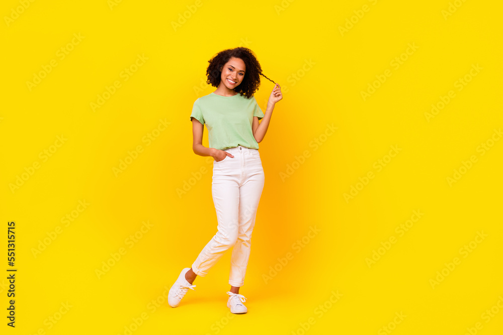 Full size photo of young attractive pretty adorable gorgeous nice woman wear green t-shirt white pants touch curls advert empty space isolated on yellow color background Full size photo of young attractive pretty adorable gorgeous nice woman wear green t-shirt white pants touch curls advert empty space isolated on yellow color background