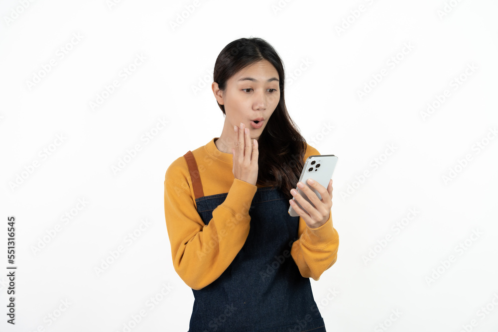 Happy young asian woman business owner wear apron and holding smartphone for checking order from customer isolated on white background for SME franchise investment concept. Happy young asian woman business owner wear apron and holding smartphone for checking order from customer isolated on white background for SME franchise investment concept.