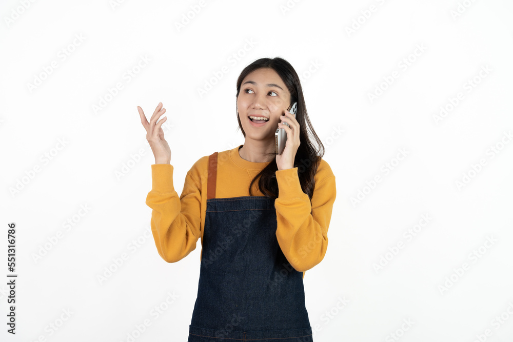 Happy young asian woman business owner wear apron and holding smartphone for checking order from customer isolated on white background for SME franchise investment concept. Happy young asian woman business owner wear apron and holding smartphone for checking order from customer isolated on white background for SME franchise investment concept.