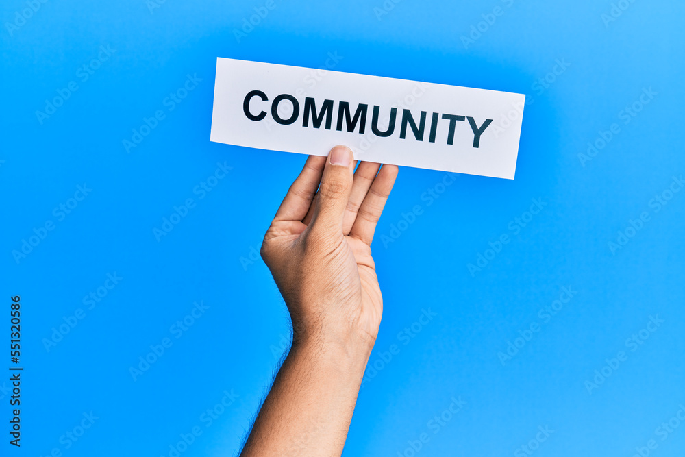 Hand of caucasian man holding paper with community word over isolated white background Hand of caucasian man holding paper with community word over isolated white background