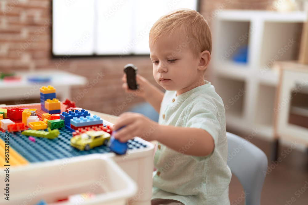 Adorable toddler playing with construction blocks holding car at kindergarten Adorable toddler playing with construction blocks holding car at kindergarten