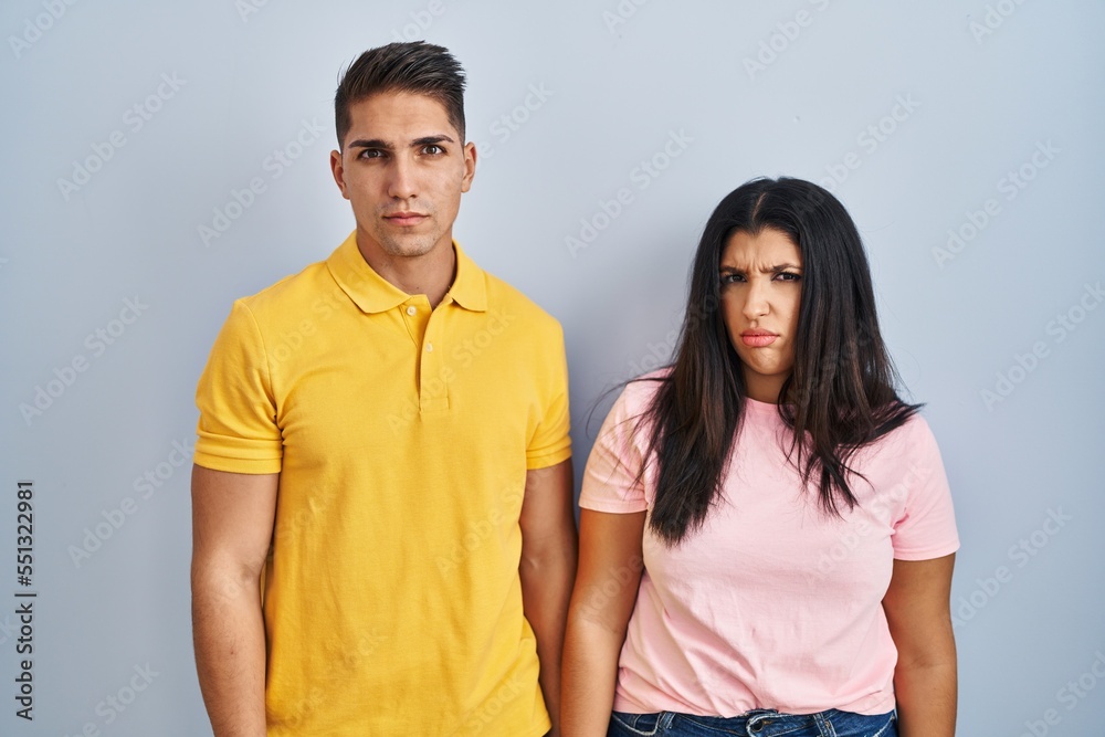 Young couple standing over isolated background skeptic and nervous, frowning upset because of problem. negative person. Young couple standing over isolated background skeptic and nervous, frowning upset because of problem. negative person.