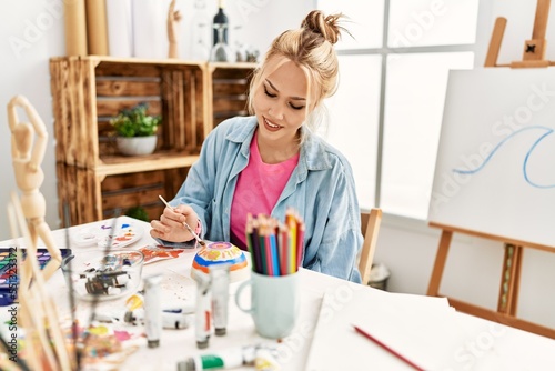 Young caucasian woman artist smiling confident drawing ceramic at art studio