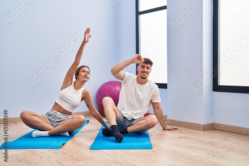 Young man and woman couple smiling confident training yoga exercise at sport center