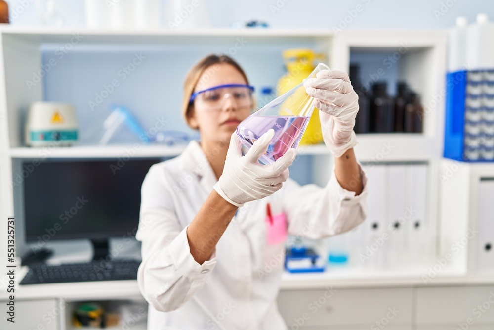 Young hispanic woman scientist measuring liquid at laboratory Young hispanic woman scientist measuring liquid at laboratory