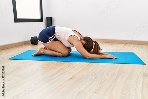 Young hispanic woman stretching at sport center