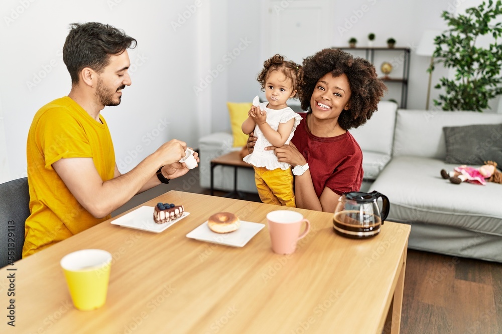 Couple and daughter having breakfast sitting on table at home Couple and daughter having breakfast sitting on table at home